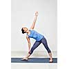 Beautiful sporty fit woman practices yoga asana utthita trikonasana - extended triangle pose beginner variation