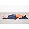 Beautiful sporty fit yogini woman relaxes in yoga asana Savasana - corpse pose in studio