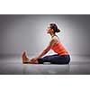 Sporty fit woman practices Ashtanga Vinyasa yoga back bending asana Paschimottanasana - seated forward bend beginner variation
