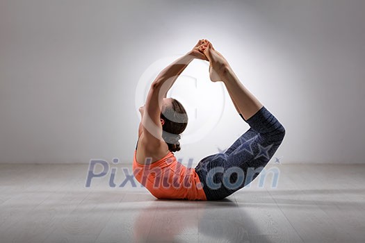 Sporty fit woman practices yoga asana Dhanurasana - bow pose Sporty fit woman practices yoga asana Dhanurasana - bow pose