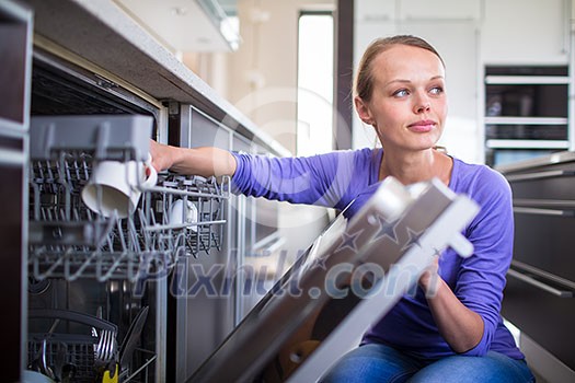 Housework: young woman putting dishes in the dishwasher Housework: young woman putting dishes in the dishwasher