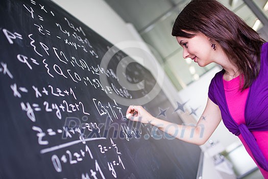 Pretty, young college student writing on the chalkboard/blackboard during a math class Pretty, young college student writing on the chalkboard/blackboard during a math class