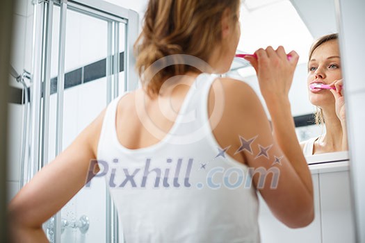 Pretty female brushing her teeth in front of mirror in the morning Pretty female brushing her teeth in front of mirror in the morning