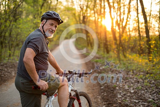 Senior man on his mountain bike outdoors (shallow DOF; color toned image)