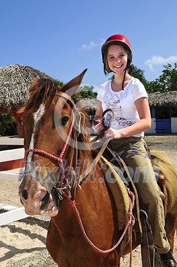Young girl riding brown horse wearing helmet Young girl riding brown horse wearing helmet