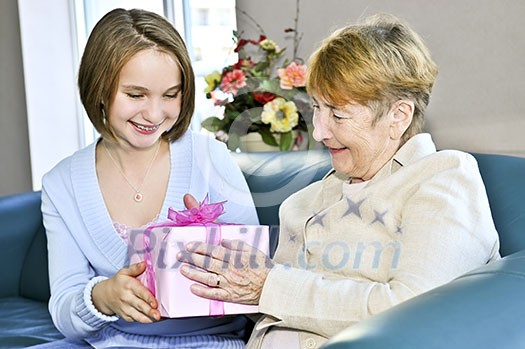 Granddaughter giving a present to her grandmother Granddaughter giving a present to her grandmother