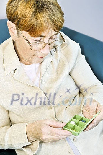 Elderly woman holding pill box with medication Elderly woman holding pill box with medication