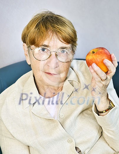 Elderly woman eating healthy holding a nutritious apple Elderly woman eating healthy holding a nutritious apple