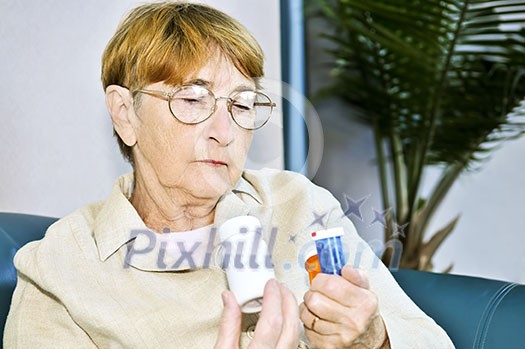 Elderly woman reading warning labels on pill bottles with medication Elderly woman reading warning labels on pill bottles with medication