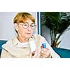 Elderly woman reading warning labels on pill bottles with medication