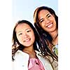 Two diverse young girlfriends smiling into camera