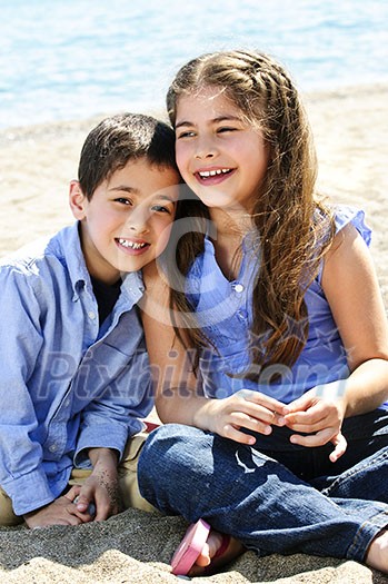 Portrait of brother and sister sitting on sand at the beach Portrait of brother and sister sitting on sand at the beach
