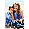 Portrait of brother and sister sitting on sand at the beach