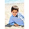 Portrait of young boy laying on sand at the beach