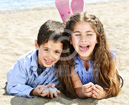 Portrait of brother and sister laying on sand at the beach Portrait of brother and sister laying on sand at the beach