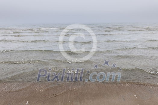 Waves coming to shore on foggy beach with fog over water. Waves coming to shore on foggy beach with fog over water.