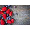 Fresh small wild strawberries and blueberries on old blue wooden background with copy space