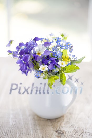 Bouquet of wild flowers in white vase on rustic wooden table near window, natural light Bouquet of wild flowers in white vase on rustic wooden table near window, natural light