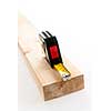 Metal imperial metric tape measure measuring two by four lumber on white background