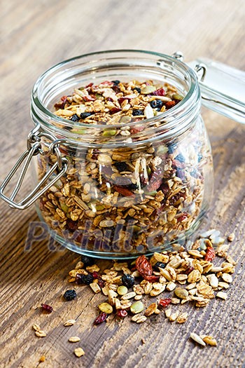 Homemade granola in open glass jar on rustic wooden background Homemade granola in open glass jar on rustic wooden background