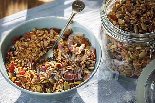 Serving of homemade granola on table with linens in morning sunlight Serving of homemade granola on table with linens in morning sunlight