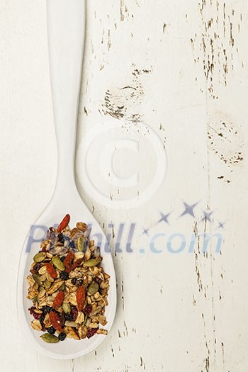 Homemade granola with various seeds and berries in white wooden spoon shot from above Homemade granola with various seeds and berries in white wooden spoon shot from above