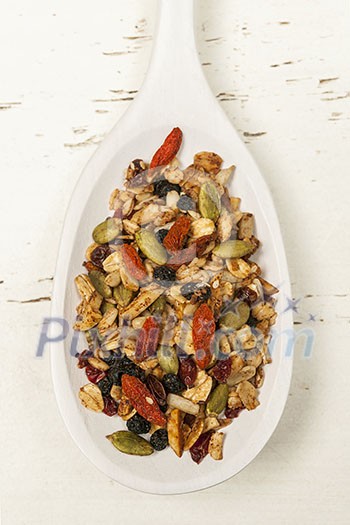 Homemade granola with various seeds and berries in white wooden spoon shot from above Homemade granola with various seeds and berries in white wooden spoon shot from above