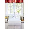 Kitchen interior with large rustic white porcelain sink and granite stone countertop under sunny window