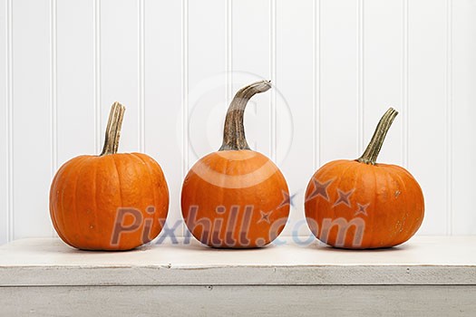 Three small pumpkins in a row against white background Three small pumpkins in a row against white background