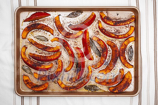 Roasted and spiced pumpkin slices on kitchen tray from above Roasted and spiced pumpkin slices on kitchen tray from above