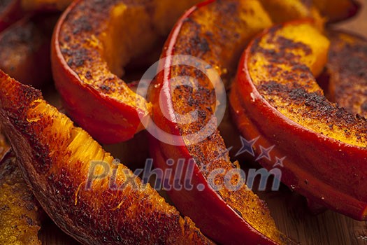 Closeup of freshly roasted pumpkin slices with spices and herbs Closeup of freshly roasted pumpkin slices with spices and herbs