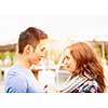 Romantic interracial young couple holding hands and looking at each other outside in sunset light