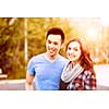 Romantic interracial young couple standing together and looking at camera outside in sunset light