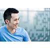 Portrait of confident young asian man in profile smiling on blue background with copy space