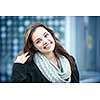 Candid portrait of young brunette woman smiling and touching her hair with copy space