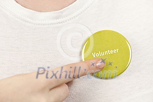 Closeup on female hand pointing to green volunteer button Closeup on female hand pointing to green volunteer button