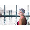 Female swimmer in an indoor swimming pool - looking at the camera, smiling wholeheartedly (shallow DOF; color toned image)