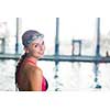 Female swimmer in an indoor swimming pool - looking at the camera, smiling wholeheartedly (shallow DOF; color toned image)