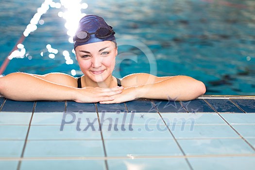 Female swimmer in an indoor swimming pool - looking at the camera, smiling wholeheartedly (shallow DOF; color toned image) Female swimmer in an indoor swimming pool - looking at the camera, smiling wholeheartedly (shallow DOF; color toned image)