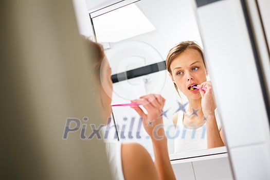 Pretty female brushing her teeth in front of mirror in the morning Pretty female brushing her teeth in front of mirror in the morning