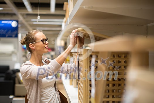 Pretty, young woman choosing the right furniture for her apartment in a modern home furnishings store (color toned image; shallow DOF) Pretty, young woman choosing the right furniture for her apartment in a modern home furnishings store (color toned image; shallow DOF)