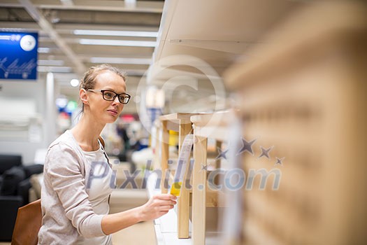 Pretty, young woman choosing the right furniture for her apartment in a modern home furnishings store (color toned image; shallow DOF) Pretty, young woman choosing the right furniture for her apartment in a modern home furnishings store (color toned image; shallow DOF)