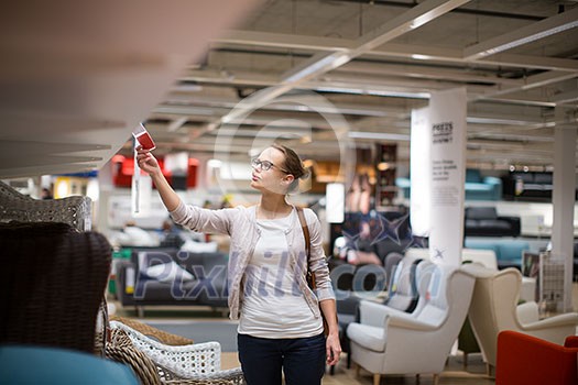 Pretty, young woman choosing the right furniture for her apartment in a modern home furnishings store (color toned image; shallow DOF) Pretty, young woman choosing the right furniture for her apartment in a modern home furnishings store (color toned image; shallow DOF)