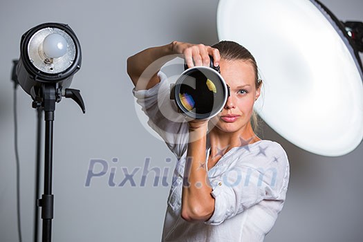 Pretty, female photographer with digital camera - DSLR and a huge telephoto lens (color toned image; shallow DOF) Pretty, female photographer with digital camera - DSLR and a huge telephoto lens (color toned image; shallow DOF)