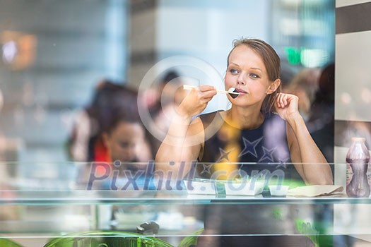 Pretty, young woman eating sushi in a restaurant, having her lunch break, enjoying the food, pausing for a while from her busy corporate/office life (color toned image) Pretty, young woman eating sushi in a restaurant, having her lunch break, enjoying the food, pausing for a while from her busy corporate/office life (color toned image)