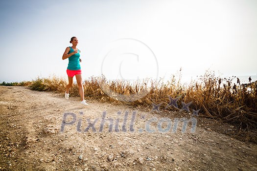 Young woman on her evening jog along the seacoast (motion blurred image) Young woman on her evening jog along the seacoast (motion blurred image)