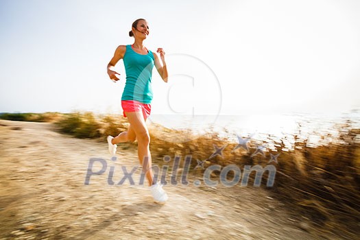 Young woman on her evening jog along the seacoast (motion blurred image) Young woman on her evening jog along the seacoast (motion blurred image)