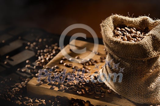 spilled coffee beans in bag on wooden table. Morning light spilled coffee beans in bag on wooden table. Morning light