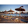 Empty beach with straw umbrellas on sunrise in Spain, Mallorca