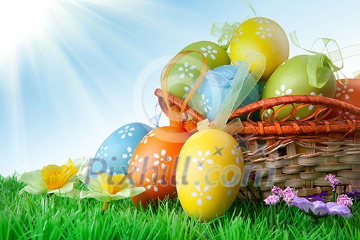 color easter eggs in basket against blue sky and clouds